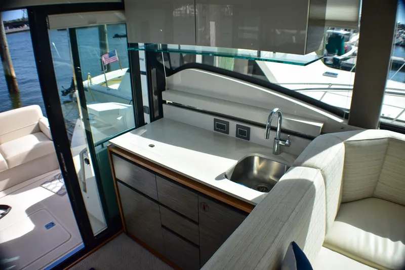 Slide: The Image of Interior of 2019 Tiara Yachts C49 Coupe, featuring a sleek kitchenette and seating area. - 24