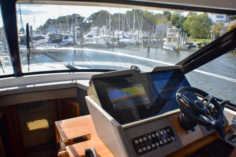 Slide: The Image of 2019 Tiara Yachts C49 Coupe helm with navigation screens, overlooking marina. - 34