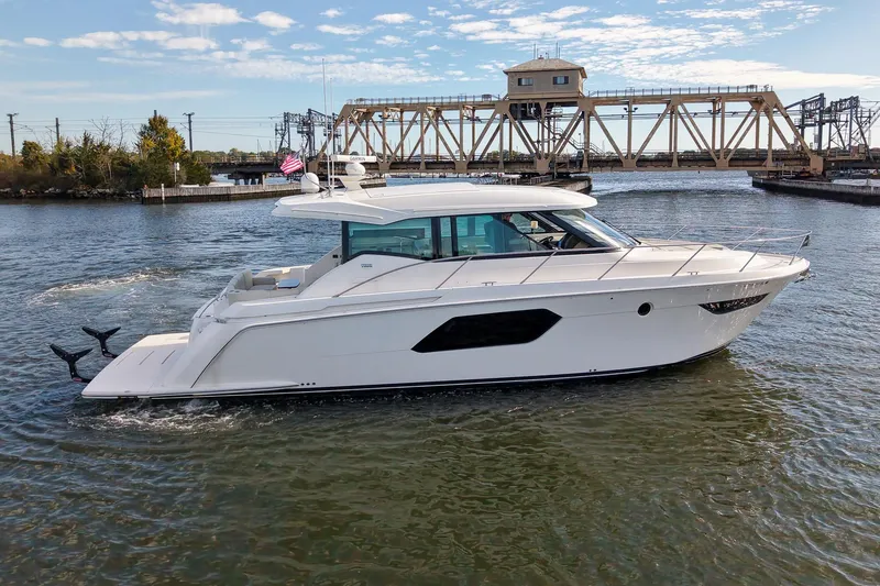 Slide: The Image of 2019 Tiara Yachts C49 Coupe cruising on a river with a bridge in the background. - 4
