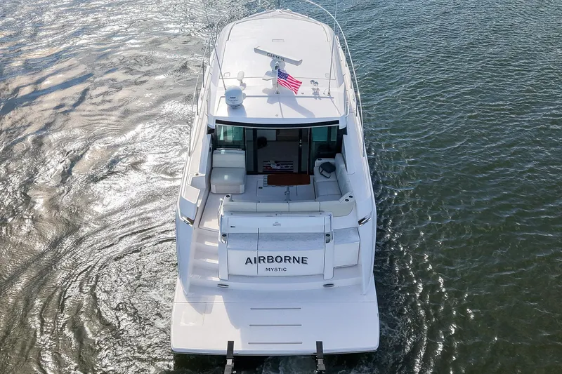 Slide: The Image of 2019 Tiara Yachts C49 Coupe cruising on water, rear view with American flag. - 8