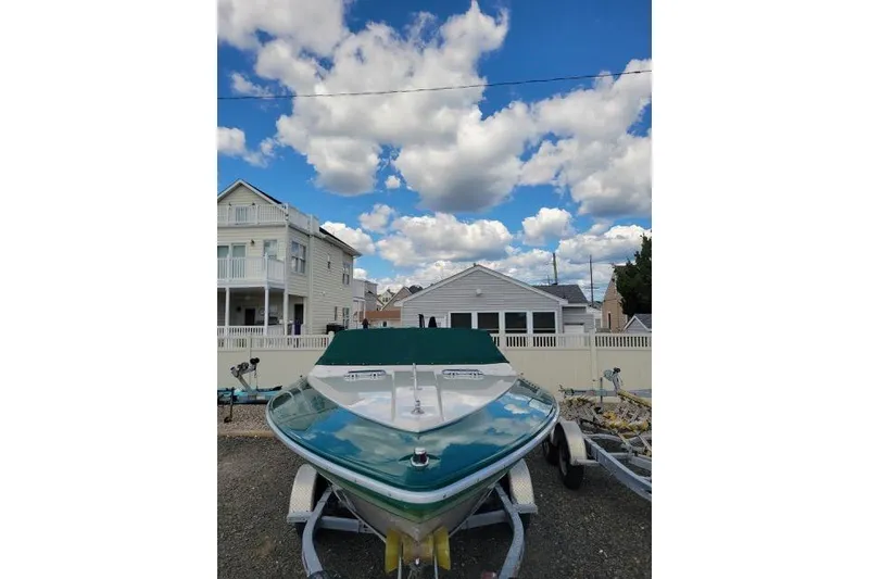 Slide: The Image of 1987 Searay Pachanga boat on trailer, parked in residential area under blue sky with clouds. - 3