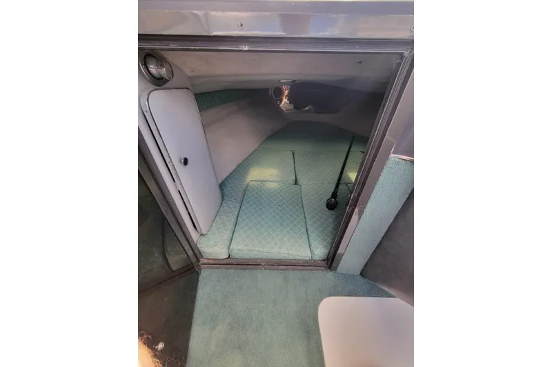 Slide: The Image of Interior cabin of 1987 Searay Pachanga boat with teal cushions and compact design. - 5