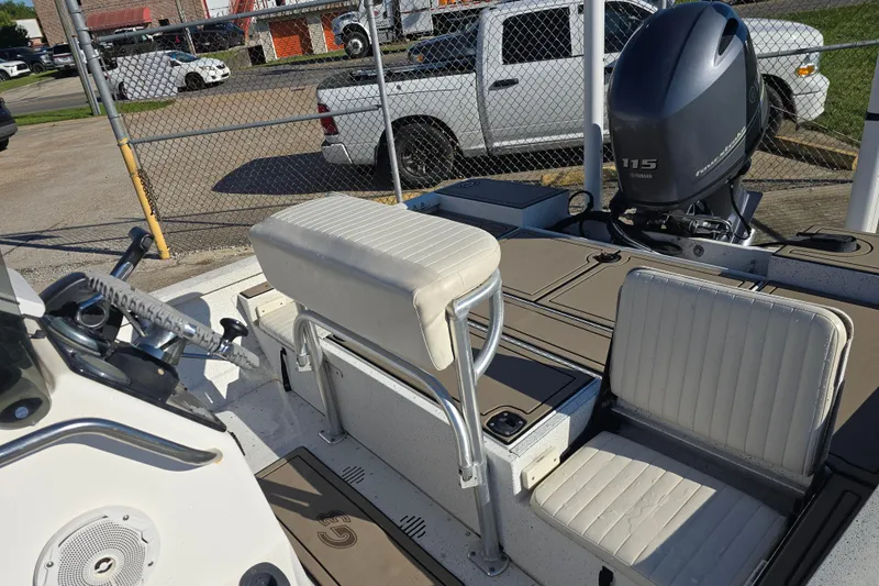 Slide: The Image of 2015 G3 Bay 18 DLX boat interior with Yamaha 115 engine, parked near a fence. - 10