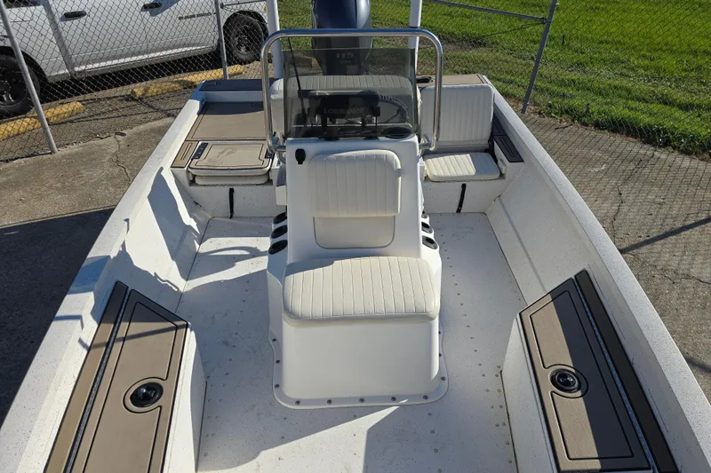 Slide: The Image of 2015 G3 Bay 18 DLX boat interior with seating and console, parked near a fence. - 15