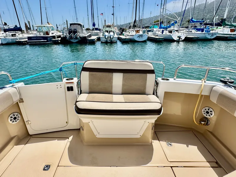 Slide: The Image of 2015 Cutwater C26 boat interior with seating, docked in a marina with sailboats. - 17