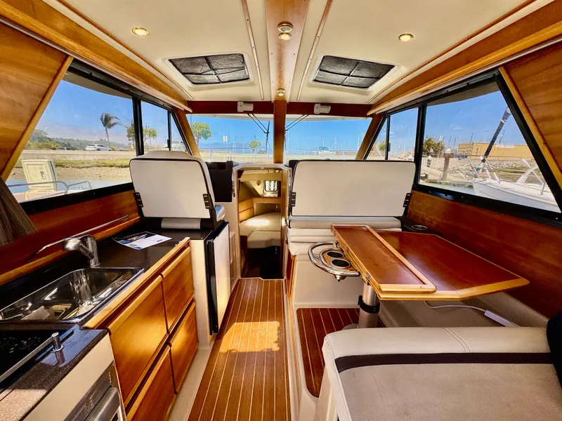 Slide: The Image of 2015 Cutwater C26 interior with wood finish, kitchenette, and seating area. - 19