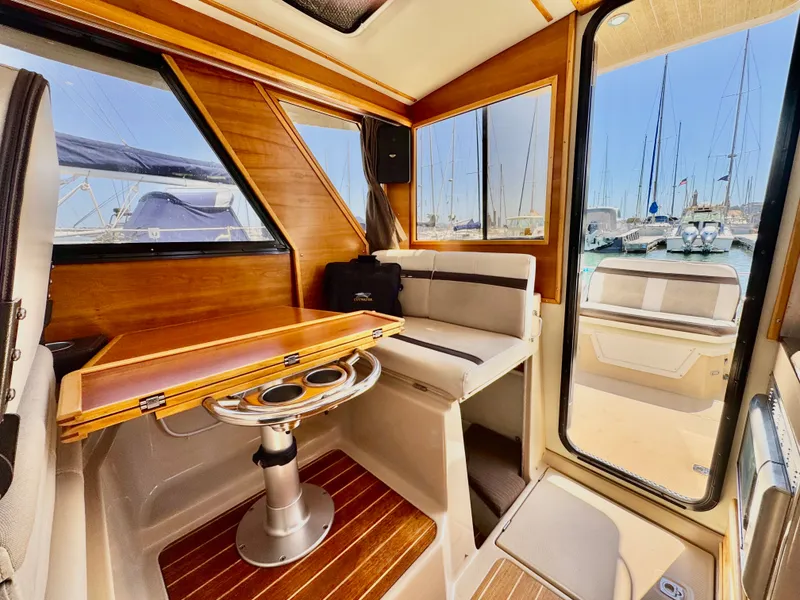 Slide: The Image of 2015 Cutwater C26 interior with wood accents, seating, and marina view through windows. - 20
