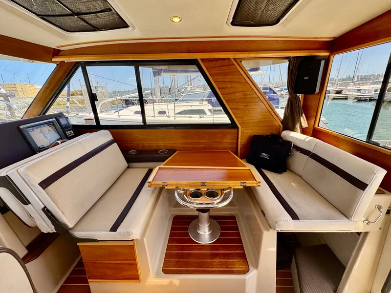Slide: The Image of 2015 Cutwater C26 interior with wood accents, seating, and table, docked at marina. - 26