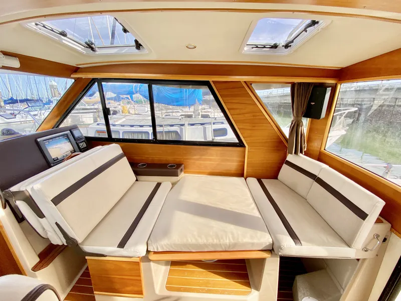 Slide: The Image of Interior of 2015 Cutwater C26 boat with beige seating and large windows. - 27