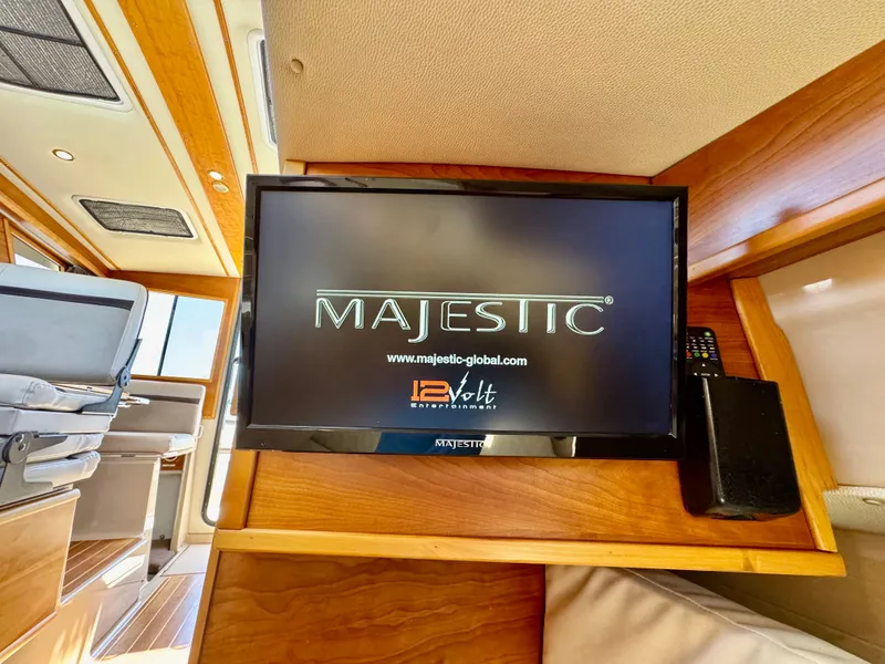 Slide: The Image of Majestic TV inside 2015 Cutwater C26 boat cabin, featuring wood paneling and seating. - 40