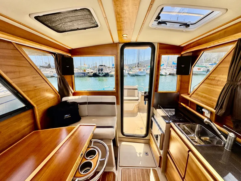 Slide: The Image of Interior of 2015 Cutwater C26 boat with wood finish, kitchenette, and marina view. - 41