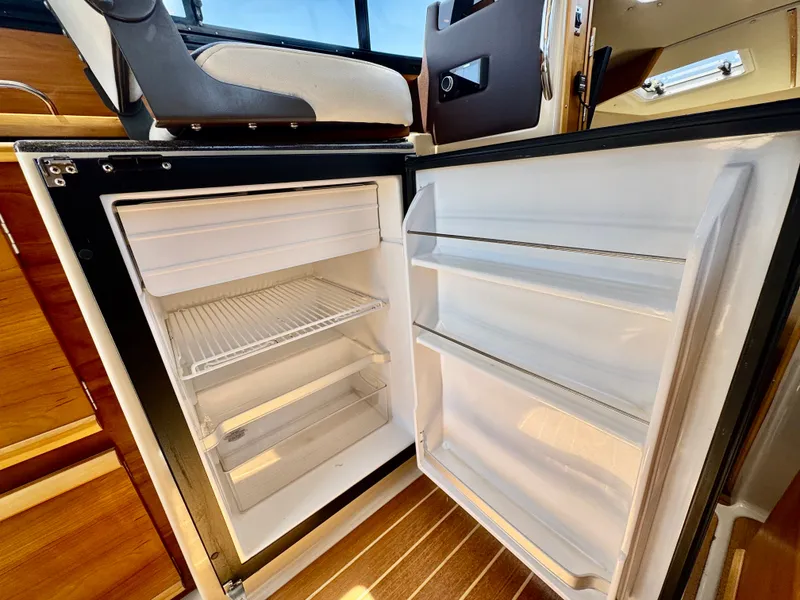 Slide: The Image of Open refrigerator inside a 2015 Cutwater C26 boat, showcasing interior storage space. - 44