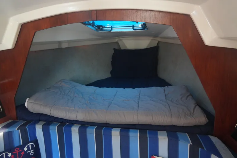 Slide: The Image of Cozy cabin interior of 1986 Hunter 28.5 sailboat with striped bedding and porthole. - 11
