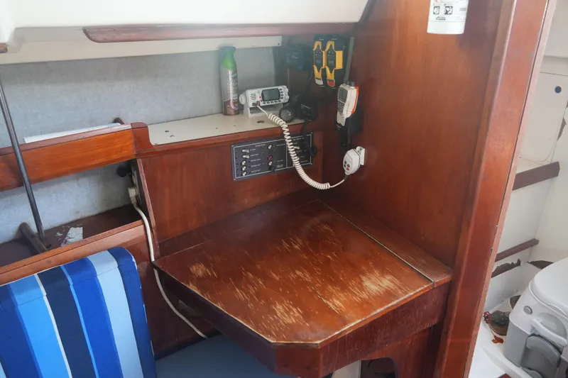 Slide: The Image of Navigation station inside 1986 Hunter 28.5 sailboat with communication equipment and wooden desk. - 14