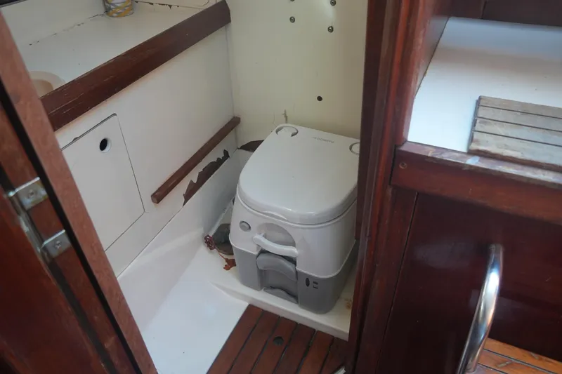 Slide: The Image of 1986 Hunter 28.5 boat interior with compact marine toilet and wooden accents. - 21
