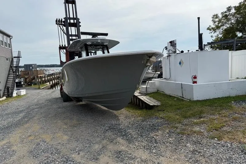 Slide: The Image of 2026 Sportsman Open 322 Center Console boat on a gravel path near a marina. - 2
