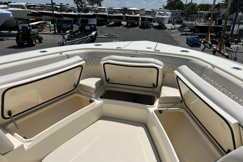 Slide: The Image of 2025 Scout 357 LXF boat interior with seating and table, parked in a marina. - 19