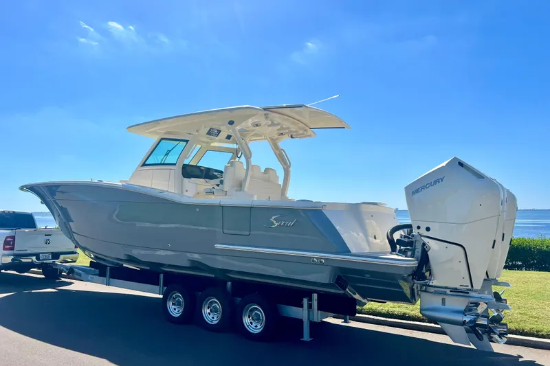 Slide: The Image of 2026 Scout 357 LXF boat on water, cityscape and palm trees in background. - 3