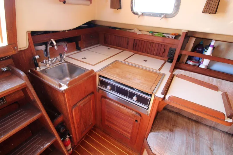 Slide: The Image of 1990 Island Packet 27 yacht interior with wooden cabinetry and compact kitchen area. - 12