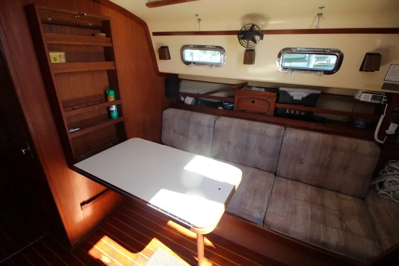 Slide: The Image of Interior of 1990 Island Packet 27 sailboat with cozy seating and wooden cabinetry. - 14