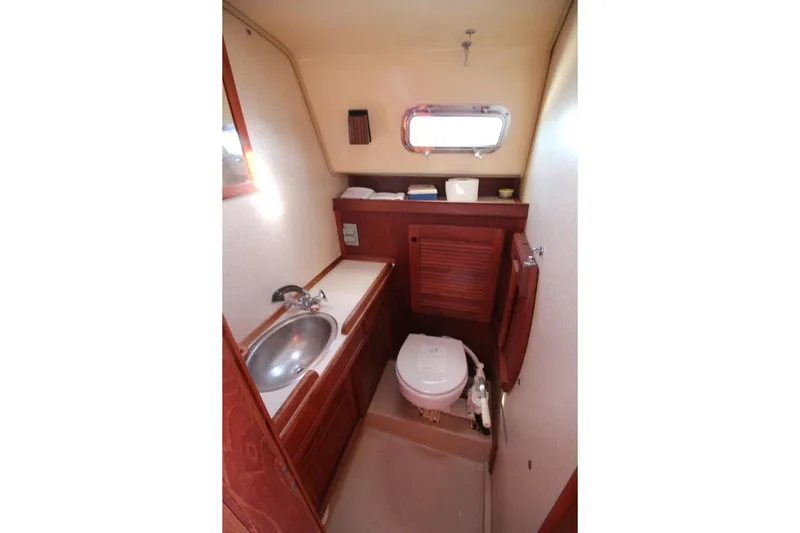 Slide: The Image of 1990 Island Packet 27 sailboat bathroom with sink, toilet, and wooden cabinetry. - 18