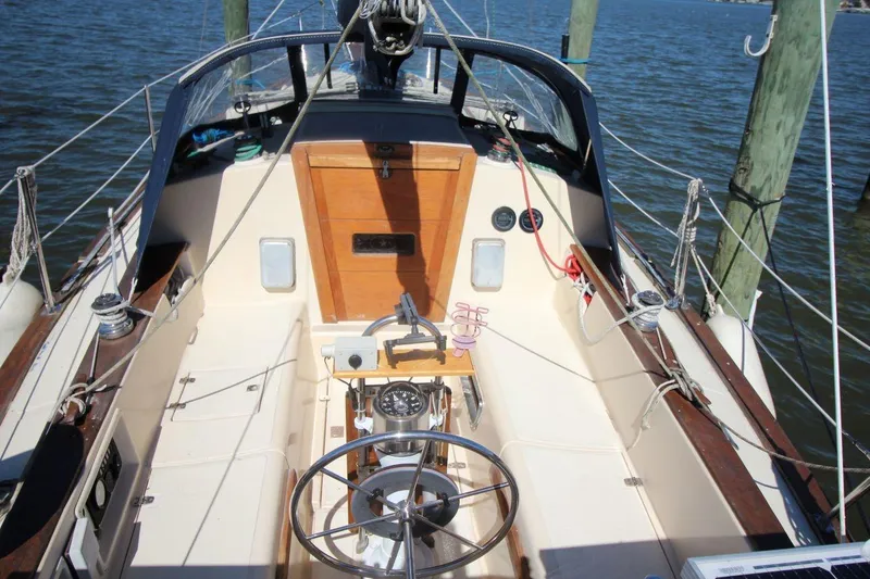 Slide: The Image of 1990 Island Packet 27 sailboat cockpit with steering wheel, compass, and wooden accents. - 6