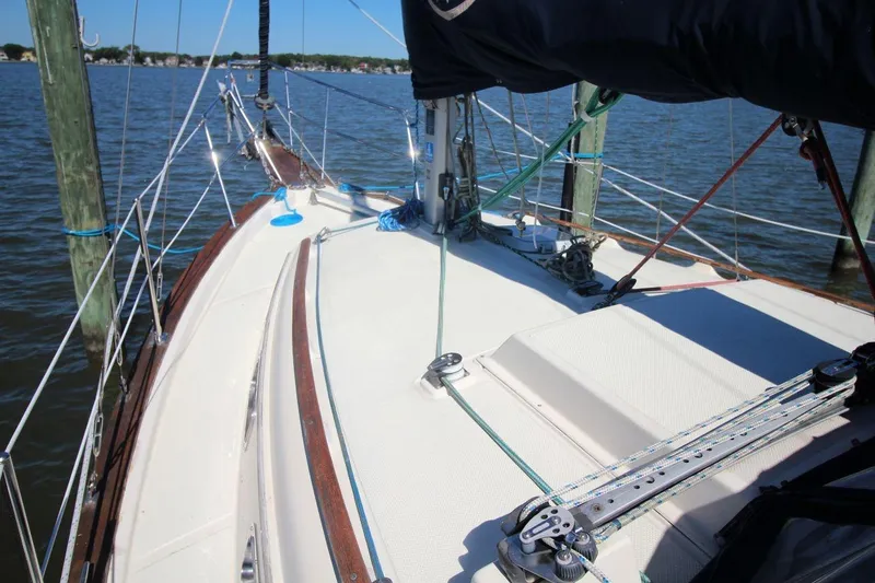 Slide: The Image of 1990 Island Packet 27 sailboat deck with rigging, docked on calm water. - 8