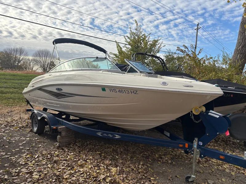 The Image of 2010 Sea Ray 210 SL SS boat on trailer, parked outdoors under cloudy sky. - 0