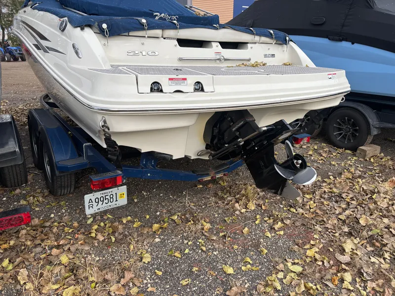 Slide: The Image of 2010 Sea Ray 210 SL SS boat on trailer, covered, with fallen leaves around. - 2