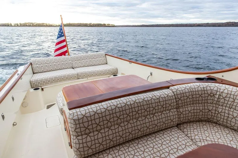Slide: The Image of 2004 Hinckley Picnic Boat EP with patterned seating and American flag on open water. - 4
