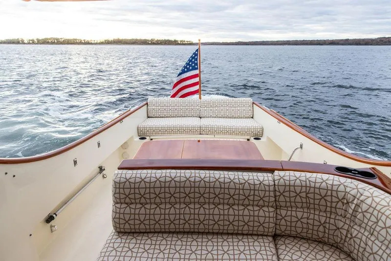 Slide: The Image of 2004 Hinckley Picnic Boat EP with American flag, elegant seating, and scenic water view. - 5