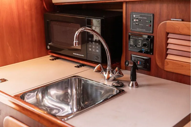 Slide: The Image of 2004 Hinckley Picnic Boat EP galley with sink, microwave, and control panels. - 19