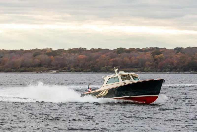 Slide: The Image of 2004 Hinckley Picnic Boat EP cruising on a scenic lake with autumn foliage. - 2