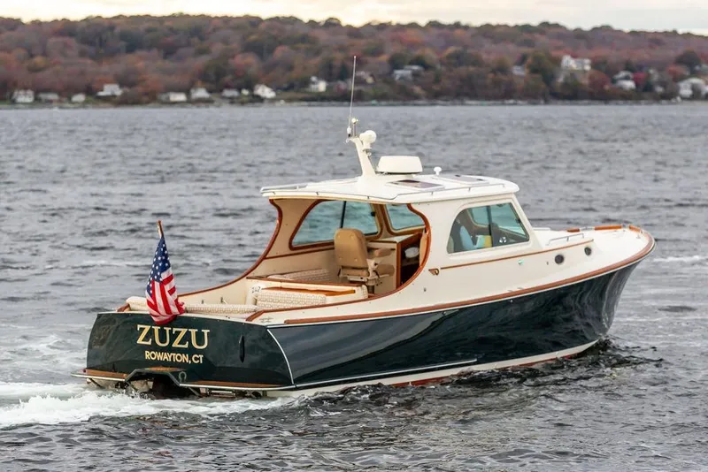 Slide: The Image of 2004 Hinckley Picnic Boat EP cruising on water with American flag, scenic background. - 3
