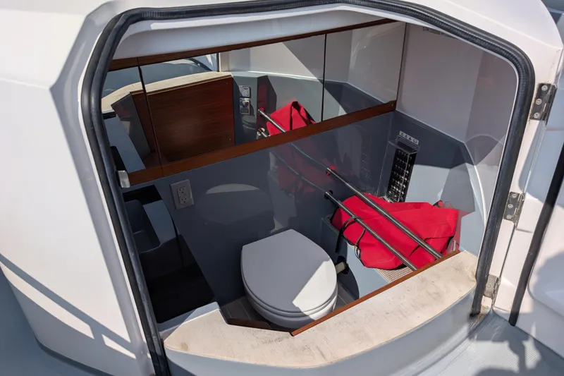 Slide: The Image of Interior of 2019 Axopar 28 CABIN boat showing compact bathroom with toilet and storage. - 41