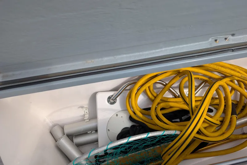 Slide: The Image of Storage compartment in 2019 Axopar 28 CABIN with yellow cables and equipment. - 17