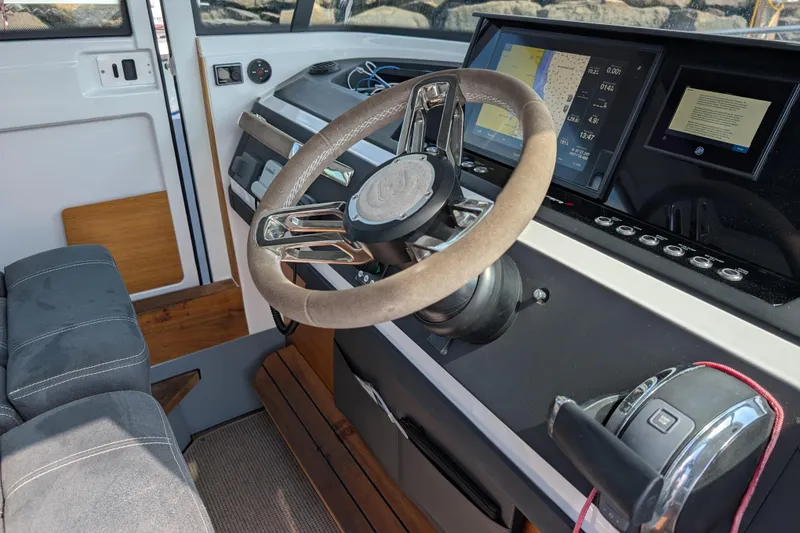 Slide: The Image of 2019 Axopar 28 CABIN boat interior with steering wheel and navigation screens. - 22