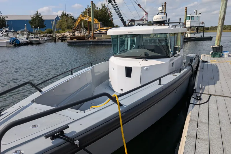 The Image of 2019 Axopar 28 CABIN boat docked at a marina with clear skies. - 0