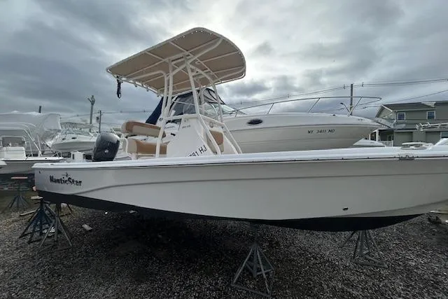 Slide: The Image of 2023 Nautistar 227XTS boat with T-top, displayed on stands, under cloudy sky. - 3
