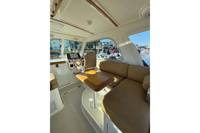Slide: The Image of Interior of a 2018 Back Cove 30 boat with beige seating and wooden table. - 16