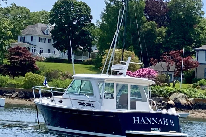 Slide: The Image of 2018 Back Cove 30 boat named "Hannah E" on water near a scenic shoreline. - 3