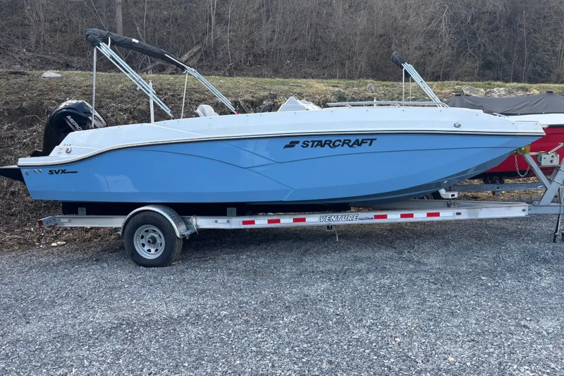 Slide: The Image of 2026 Starcraft SVX 211 OB boat on trailer, blue hull, parked outdoors. - 11