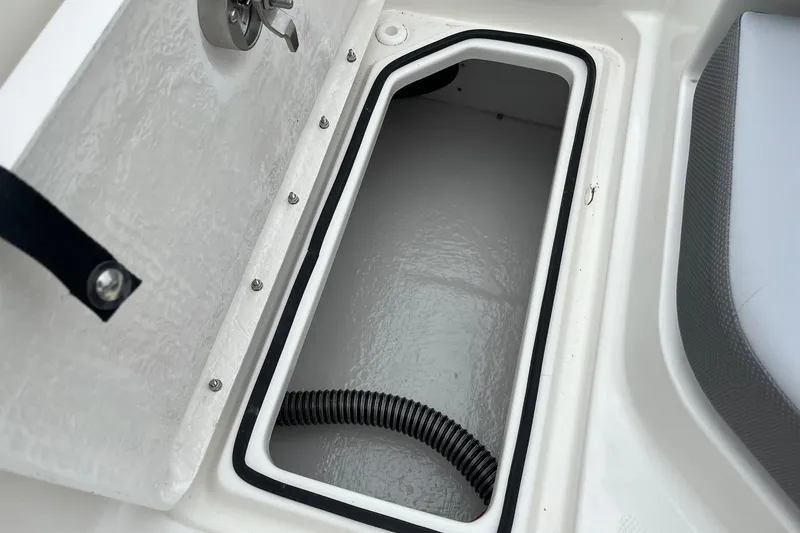 Slide: The Image of 2026 Bayliner V20 boat storage compartment with open hatch and visible hose. - 17