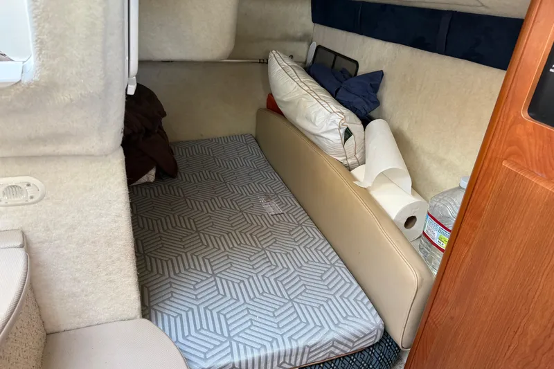 Slide: The Image of 2006 Bayliner 245 Cruiser cabin interior with bed, pillows, and storage items. - 11