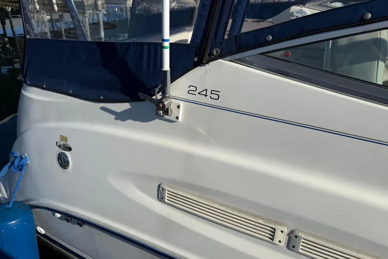 Slide: The Image of 2006 Bayliner 245 Cruiser boat with blue canopy and docked at marina. - 3