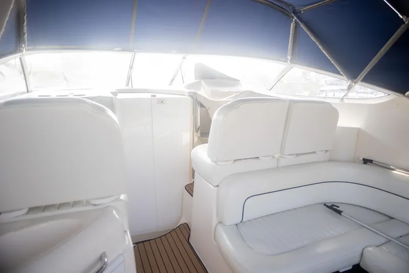 Slide: The Image of Interior of 1999 Bayliner 3055 Ciera Sunbridge with white seating and blue canopy. - 10