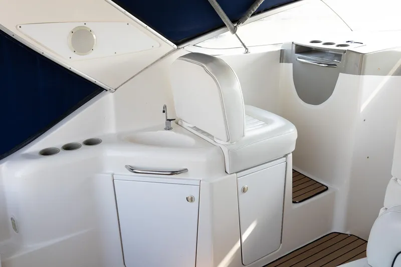 Slide: The Image of 1999 Bayliner 3055 Ciera Sunbridge interior with white seating and compact sink area. - 12