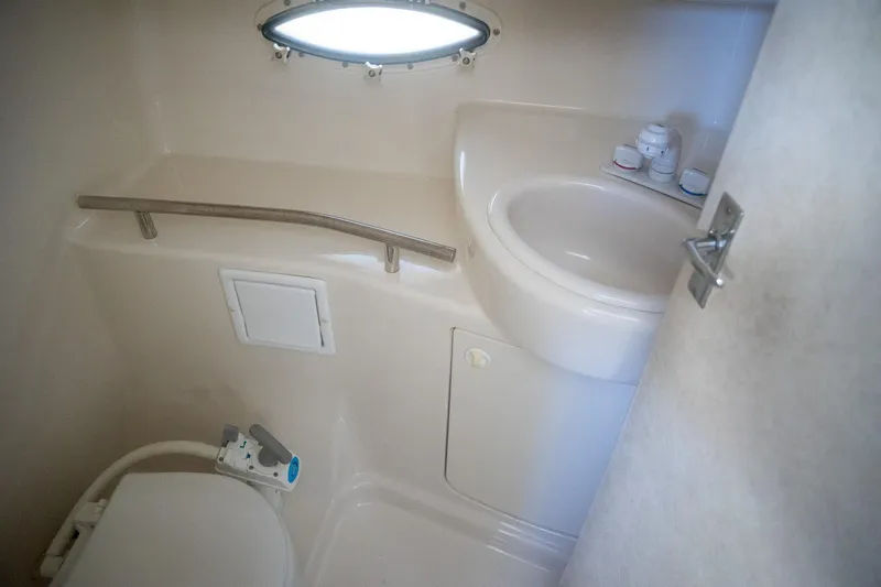Slide: The Image of 1999 Bayliner 3055 Ciera Sunbridge bathroom with sink, toilet, and porthole window. - 18