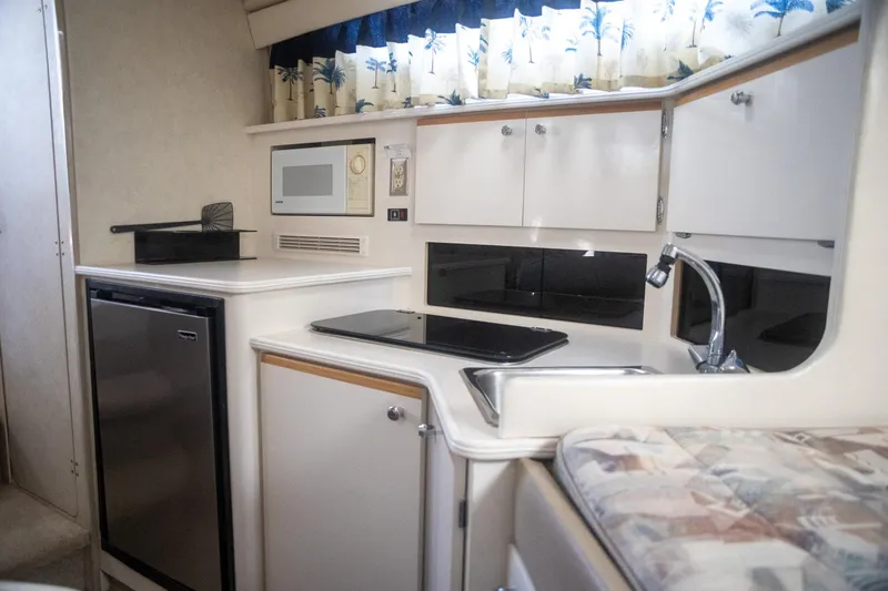 Slide: The Image of 1999 Bayliner 3055 Ciera Sunbridge interior kitchen with microwave, fridge, and sink. - 22