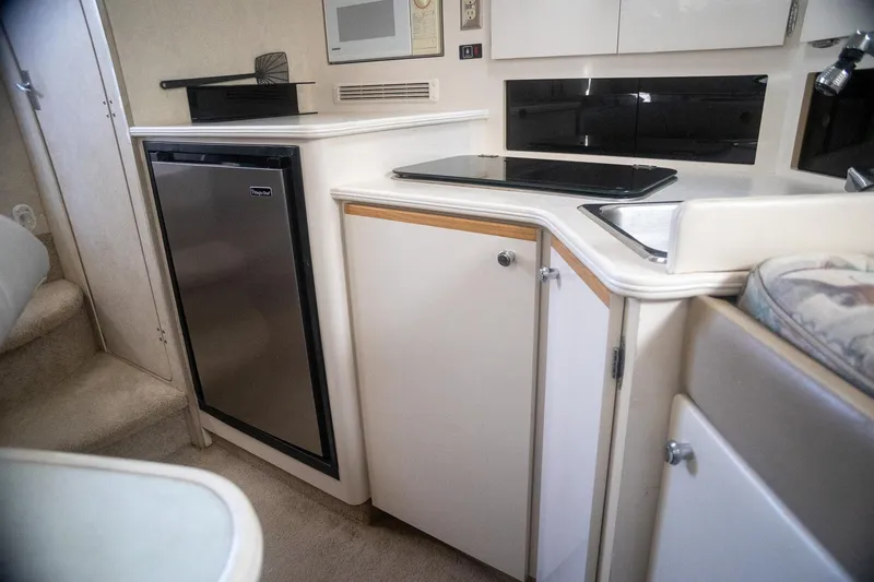 Slide: The Image of 1999 Bayliner 3055 Ciera Sunbridge interior kitchen with fridge, stove, and cabinets. - 23